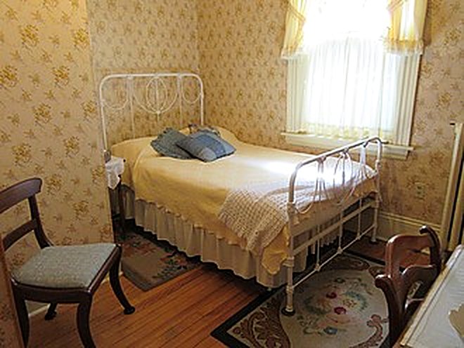 Guest bedroom with iron bed and yellow curtains